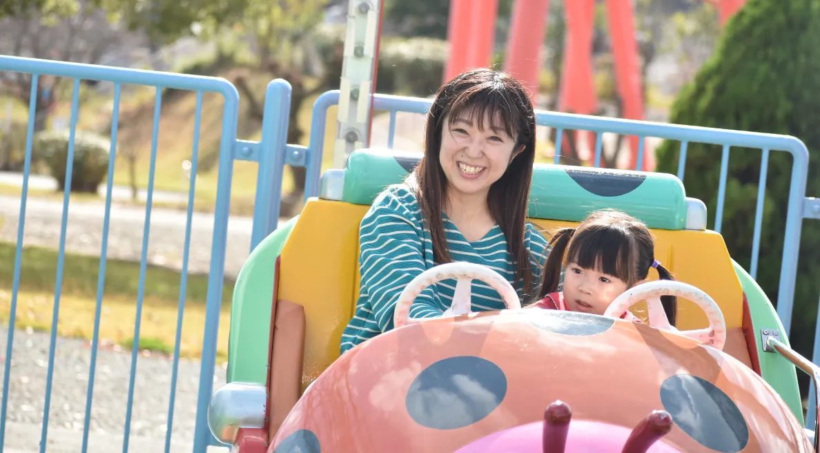 写真：てんとう虫の車タイプの乗り物に乗っている、お母さんと小さい女のお子さん